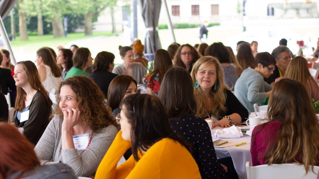 Women talking at tables in a tent at a Women+ in Green event